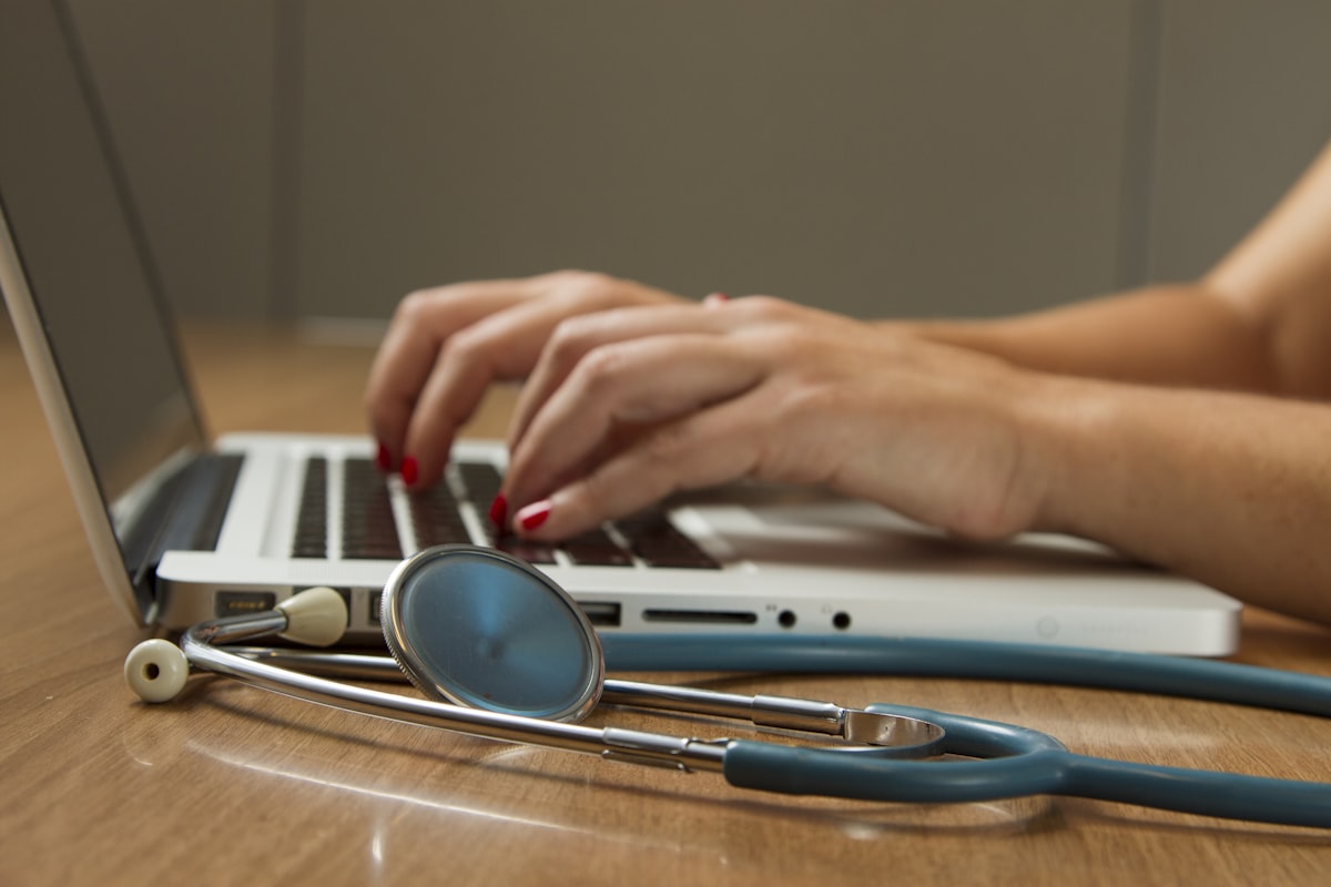Medizinerin arbeitet am Laptop neben einem Stethoskop